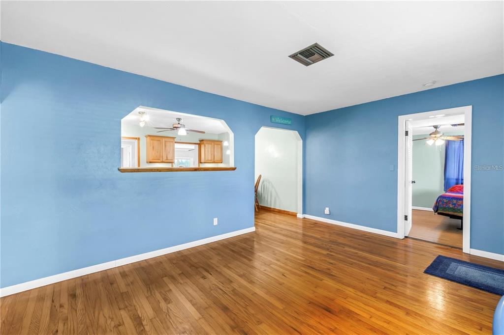 A living room with blue walls, hardwood floors, and an opening into the kitchen — 6144 2ND AVENUE N, ST PETERSBURG, FL