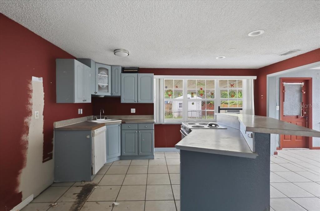 A kitchen with blue cabinets, red walls, tile flooring, and a breakfast bar — 2605 YALE ROAD, SOUTH DAYTONA, FL