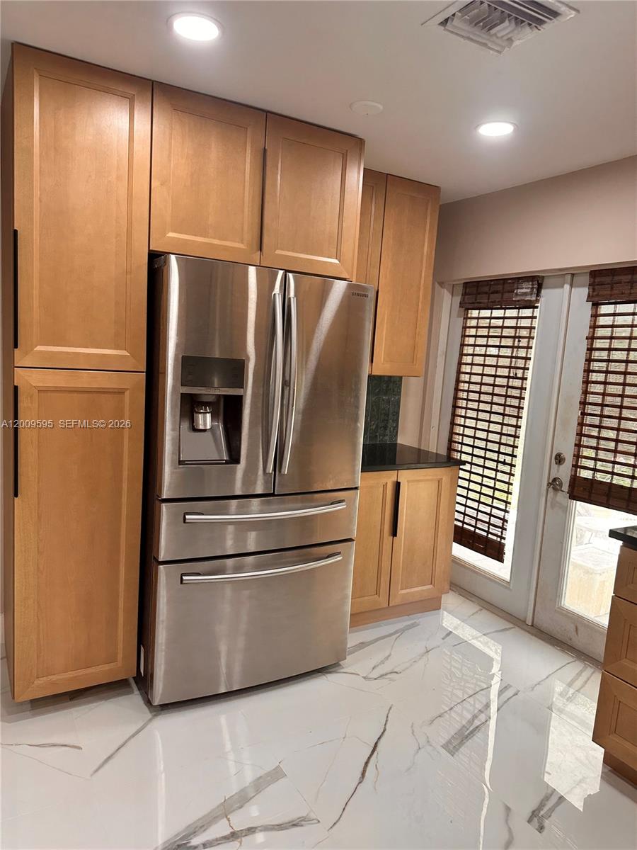 A kitchen features light wood cabinets, stainless steel appliances, and white marble-patterned tile flooring — 3614 Everglades Rd, Palm Beach Gardens FL 33410, PALM BEACH GARDENS, FL