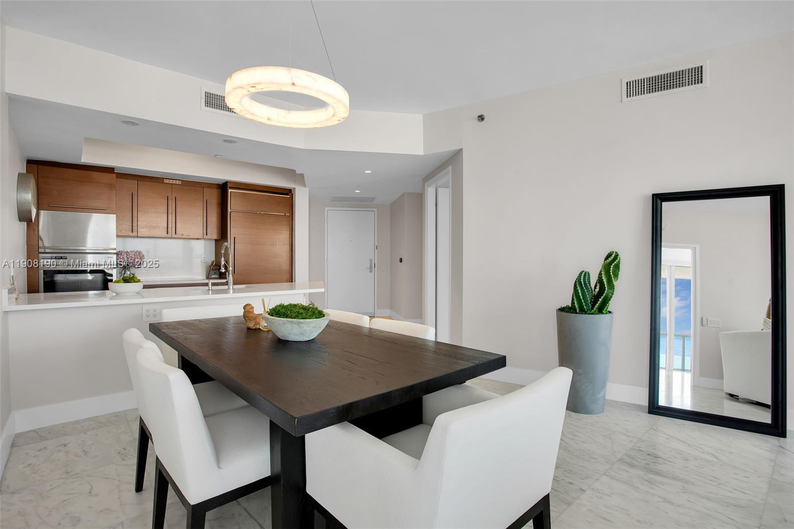 A dining area features a dark wood table, white chairs, and a large floor mirror — 450 Alton Rd # 2110, Miami Beach FL 33139, MIAMI BEACH, FL