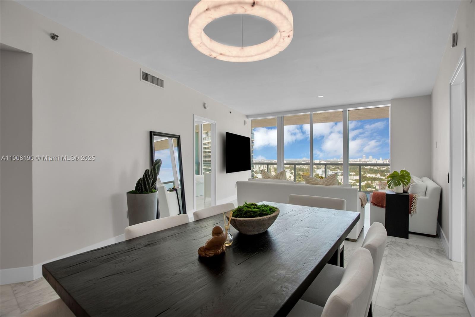 A dining area with a dark wooden table overlooks a living room and city skyline — 450 Alton Rd # 2110, Miami Beach FL 33139, MIAMI BEACH, FL