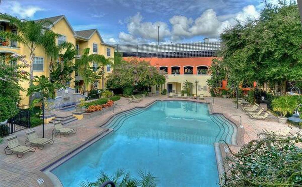An outdoor swimming pool surrounded by a brick patio, lounge chairs, and multi-story apartment buildings — 1910 E PALM AVENUE UNIT 11117, TAMPA, FL