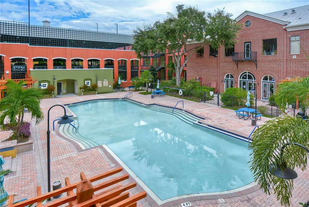 An outdoor swimming pool is surrounded by a brick patio and multi-story building facades — 1910 E PALM AVENUE UNIT 11117, TAMPA, FL