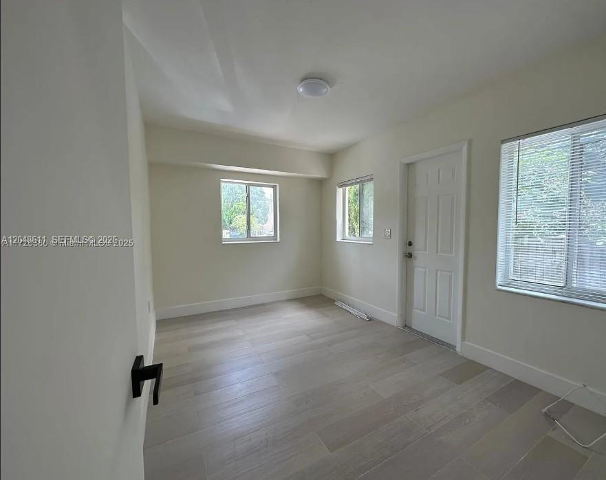 An empty room with light-colored wood-look tile flooring, white walls, and three windows — 1514 SW 6th St # 4, Miami FL 33135, MIAMI, FL