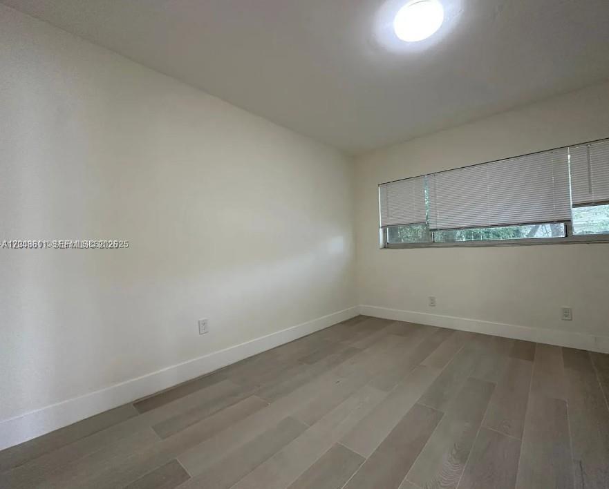 An empty room features light-colored walls, wood-look tile flooring, and a window with blinds — 1514 SW 6th St # 4, Miami FL 33135, MIAMI, FL