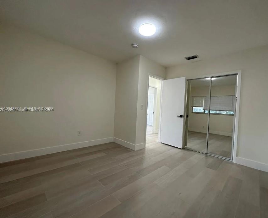 A bedroom with light-colored wood flooring, a mirrored closet, and a doorway leading to a hallway — 1514 SW 6th St # 4, Miami FL 33135, MIAMI, FL