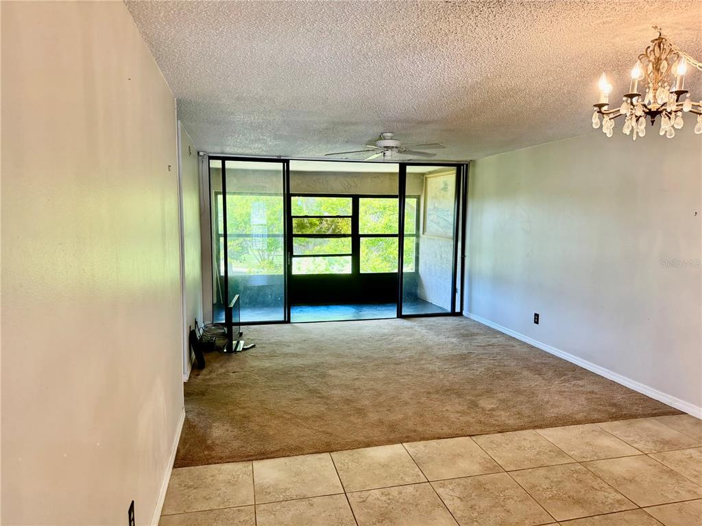 A living room with beige carpet, tile flooring, a ceiling fan, and a screened balcony — 12300 VONN ROAD UNIT 5304, LARGO, FL