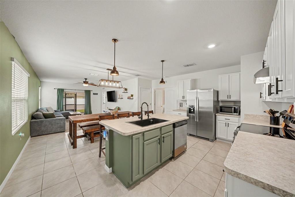 An open-concept kitchen features a green island, stainless steel appliances, and an adjacent dining area — 6784 HUNTLEIGH HAMMOCK ROAD, ST CLOUD, FL