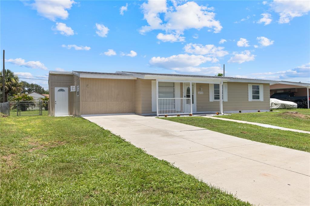 A single-story house with tan siding, a concrete driveway, and a small covered front porch — 22312 LASALLE ROAD, PORT CHARLOTTE, FL