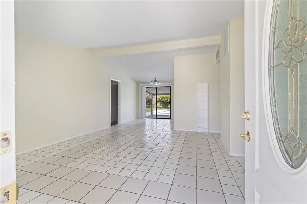 An interior view of a tiled living area looking toward a sliding glass door — 22312 LASALLE ROAD, PORT CHARLOTTE, FL