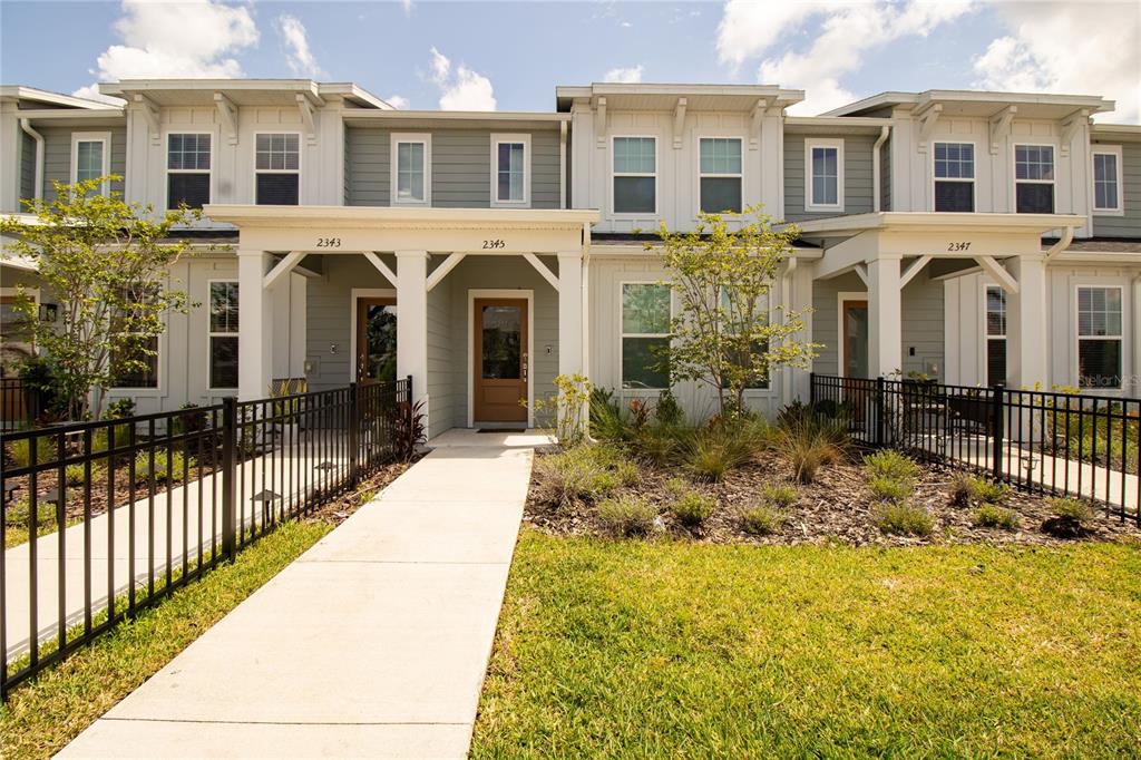 A row of two-story townhouses with gray siding, white trim, and covered front porches — 2345 SOUTHBURY, KISSIMMEE, FL