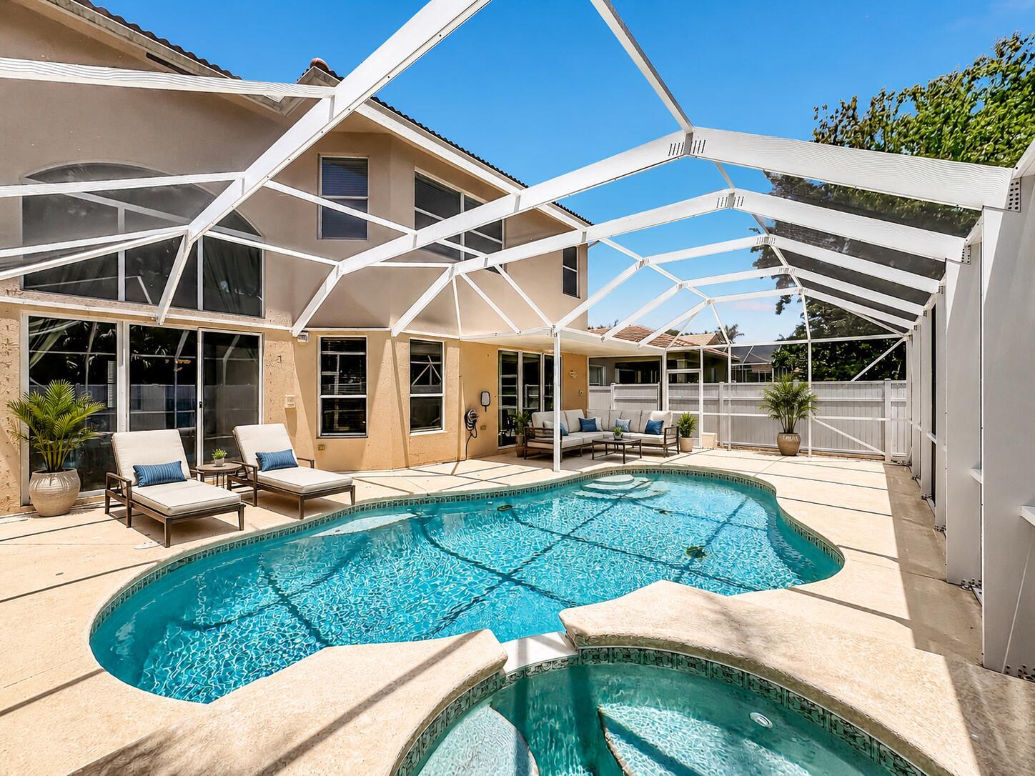 A swimming pool and hot tub sit inside a screened-in patio behind a two-story house — 5747 Sunberry Circle, Fort Pierce FL 34951, FORT PIERCE, FL