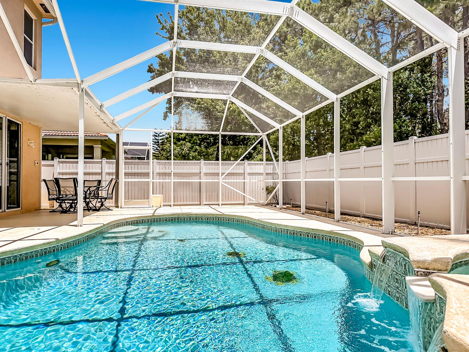 A swimming pool with a waterfall feature is enclosed by a white screened lanai structure — 5747 Sunberry Circle, Fort Pierce FL 34951, FORT PIERCE, FL