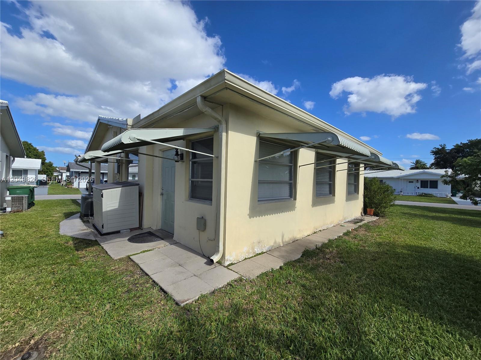 A yellow exterior wall of a house features metal awnings over several windows — 4805 NW 45th Ave, Tamarac FL 33319, TAMARAC, FL