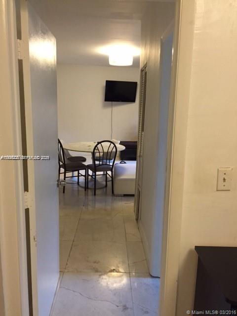 A view through a doorway into a dining area with a table, chairs, and television — 842 Meridian Ave # 1B, Miami Beach FL 33139, MIAMI BEACH, FL