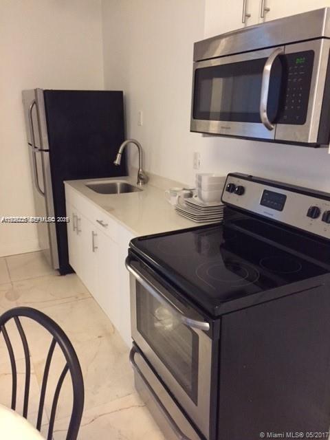A kitchen features white cabinets, stainless steel appliances, a sink, and light-colored tile flooring — 842 Meridian Ave # 1B, Miami Beach FL 33139, MIAMI BEACH, FL