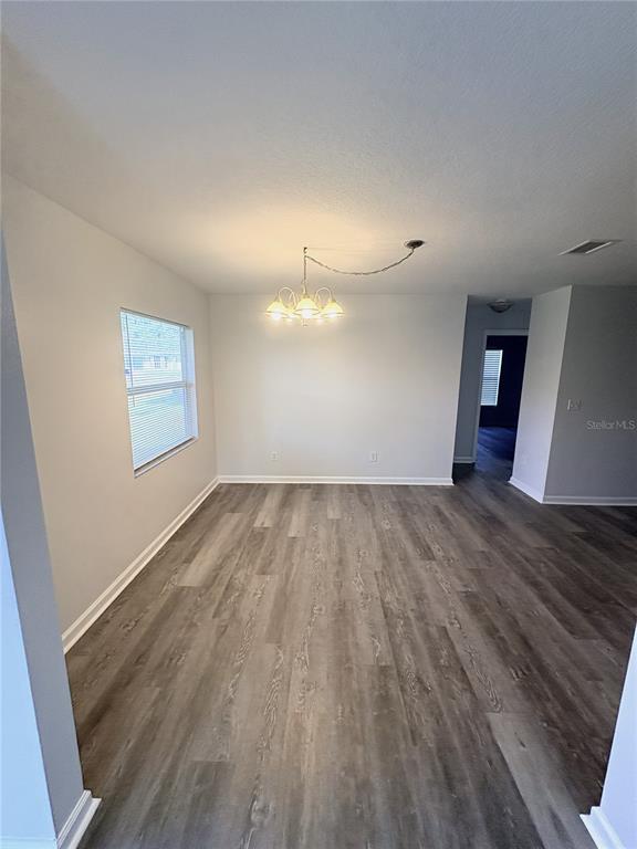 A dining area features light gray walls, wood-look flooring, and a hanging chandelier — 2829 NORDMAN AVENUE, NEW SMYRNA BEACH, FL