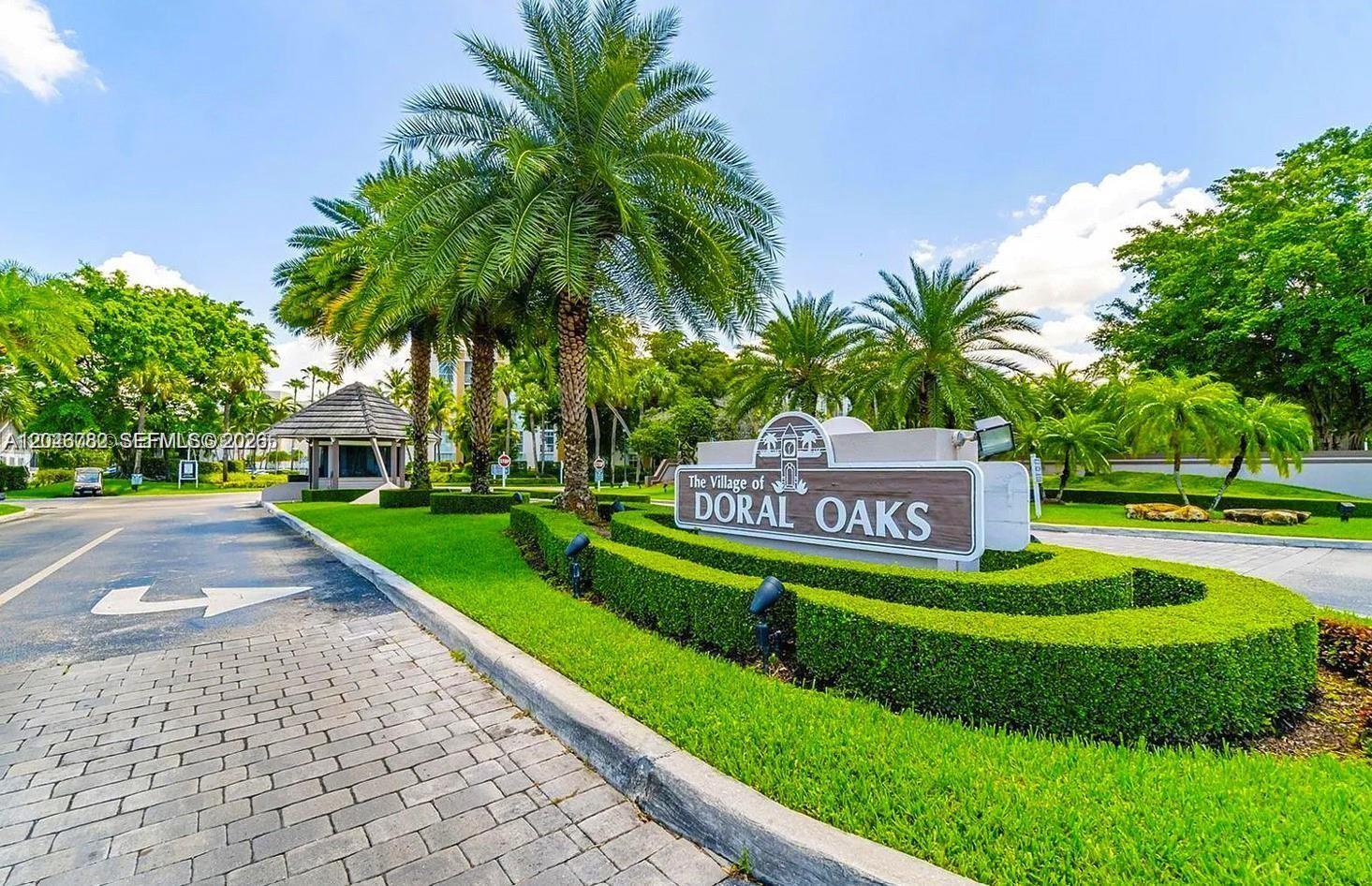 A sign for The Village of Doral Oaks stands in front of palm trees and landscaping — 9725 NW 52nd St # 210, Doral FL 33178, DORAL, FL