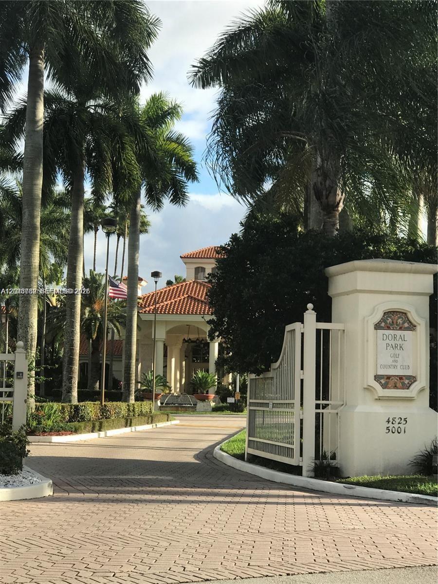 A paved driveway leads to the entrance of a building with a tiled roof — 9725 NW 52nd St # 210, Doral FL 33178, DORAL, FL