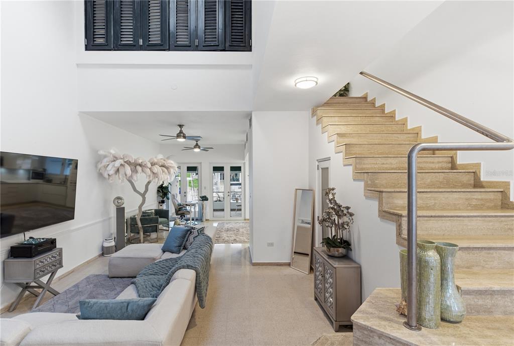 A living room features a stone staircase, white walls, and a view toward glass doors — 25 PLAZA MAYOR, HUMACAO, PR