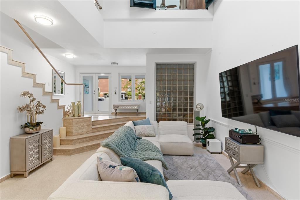 A living room features a large sectional sofa, a wall-mounted television, and a glass-block wall — 25 PLAZA MAYOR, HUMACAO, PR