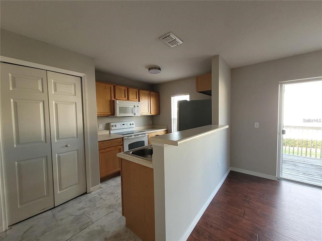 A kitchen features wood cabinets, white appliances, a breakfast bar, and a sliding glass door — 3805 EXETER LANE, LAKELAND, FL