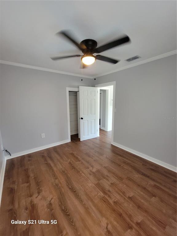 A bedroom with light gray walls, wood-look flooring, a ceiling fan, and an open closet — 16 S PRIMROSE DRIVE, ORLANDO, FL