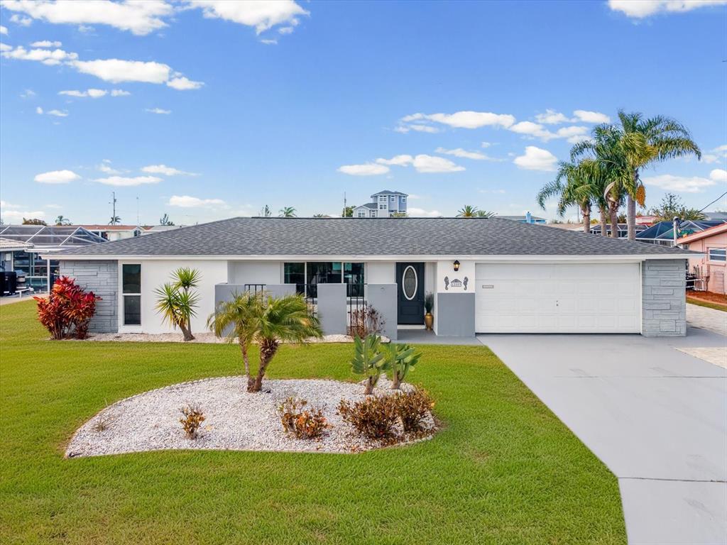 A single-story house with a gray roof, white walls, and a two-car garage — 12809 4TH ISLE, HUDSON, FL