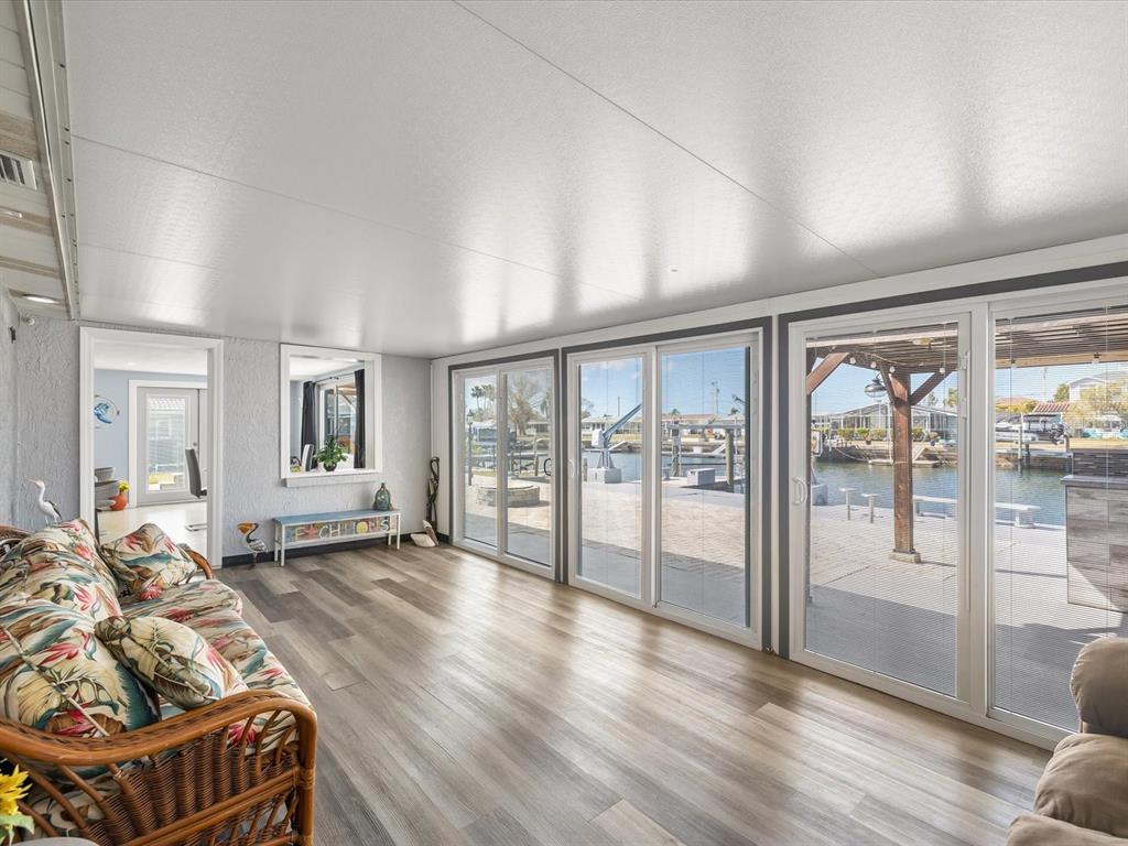 A sunroom with wood-look flooring and sliding glass doors overlooking a canal and boat dock — 12809 4TH ISLE, HUDSON, FL