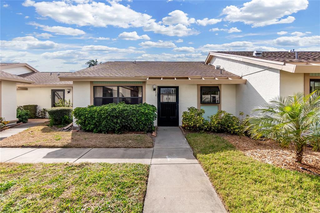 A single-story residential building with a concrete walkway leading to a black front door — 6135 HERITAGE LANE UNIT 6135, BRADENTON, FL