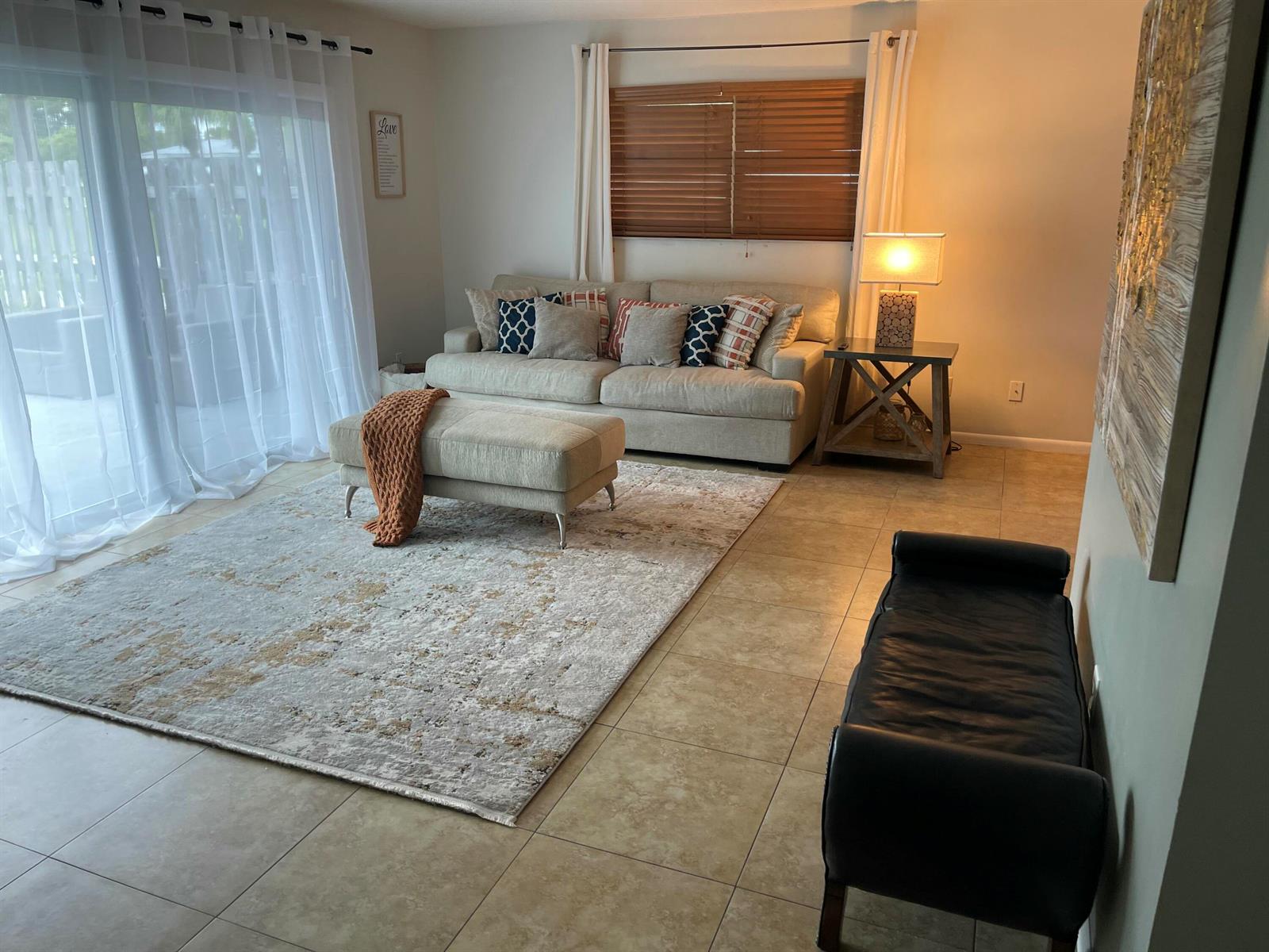 A living room features a beige sofa, matching ottoman, area rug, and a black bench — 187 Auburn Drive, FL 33460, FL