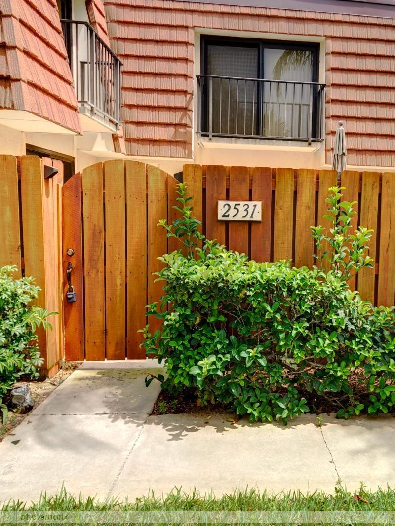 A wooden gate and fence stand before a two-story building with a balcony — 2531 25th Court, Jupiter FL 33477, JUPITER, FL