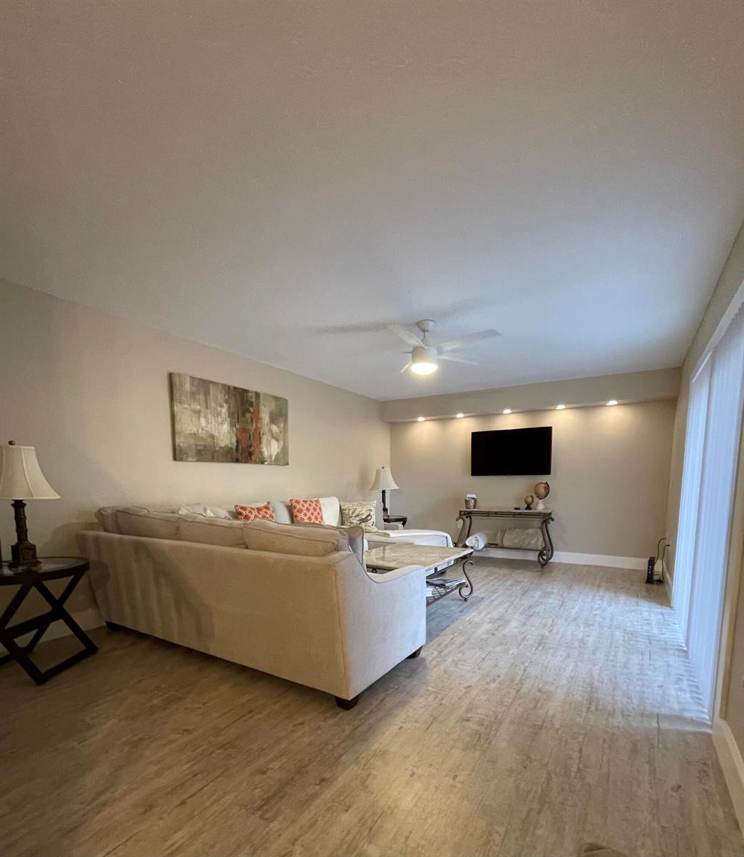 A living room features a sectional sofa, a wall-mounted television, and wood-look flooring — 2531 25th Court, Jupiter FL 33477, JUPITER, FL