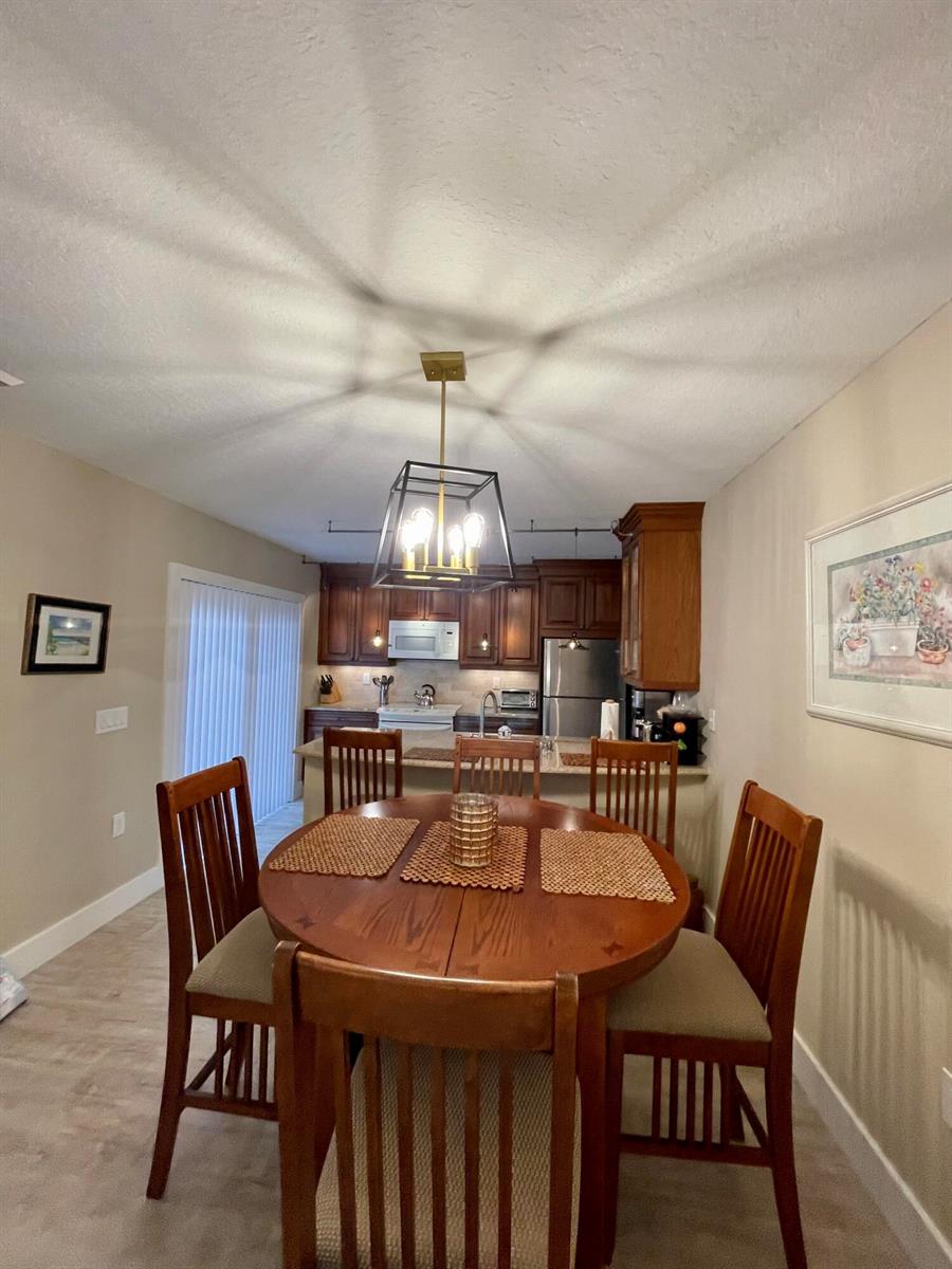 A dining area with a round wooden table and chairs sits in front of a kitchen — 2531 25th Court, Jupiter FL 33477, JUPITER, FL