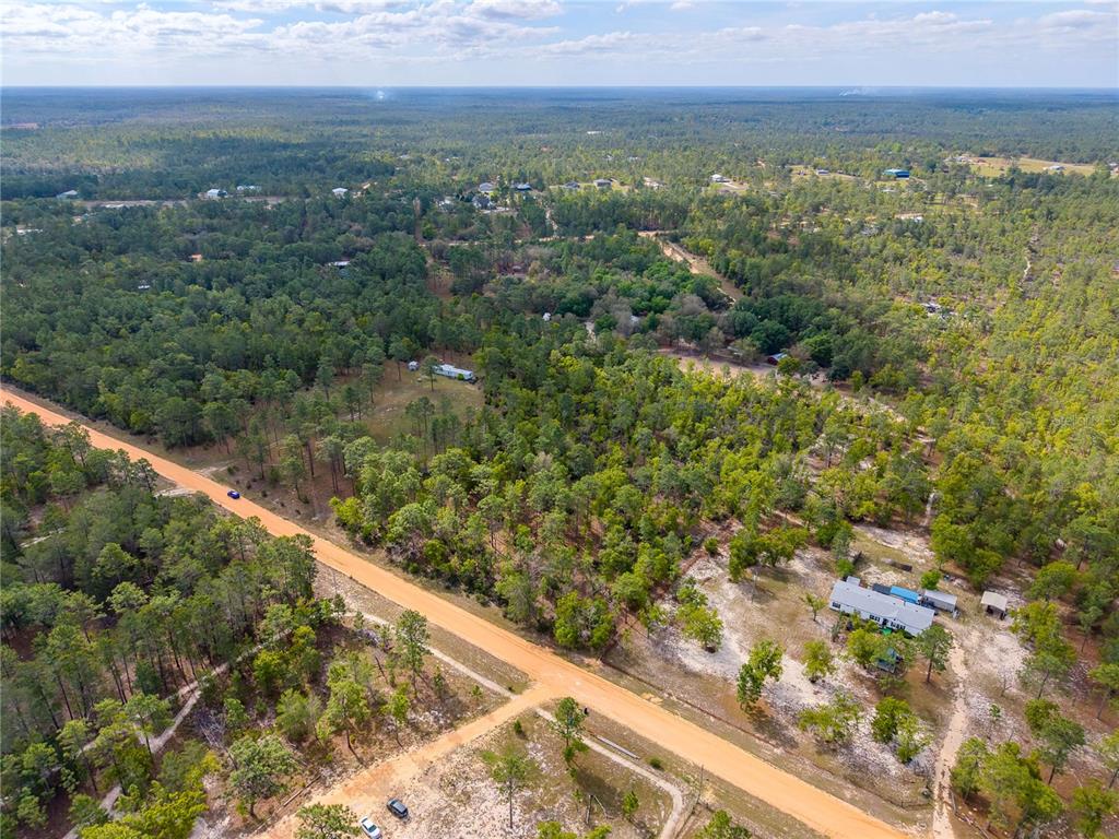 An aerial view shows a dirt road intersecting through a wooded area with scattered houses — 230 MELROSE LANDING DRIVE, HAWTHORNE, FL