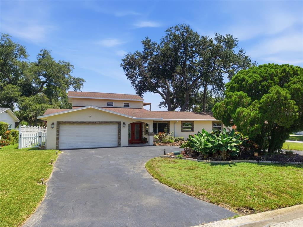 A single-story house with a two-car garage, red front door, and a large oak tree — 701 58TH AVENUE S, ST PETERSBURG, FL