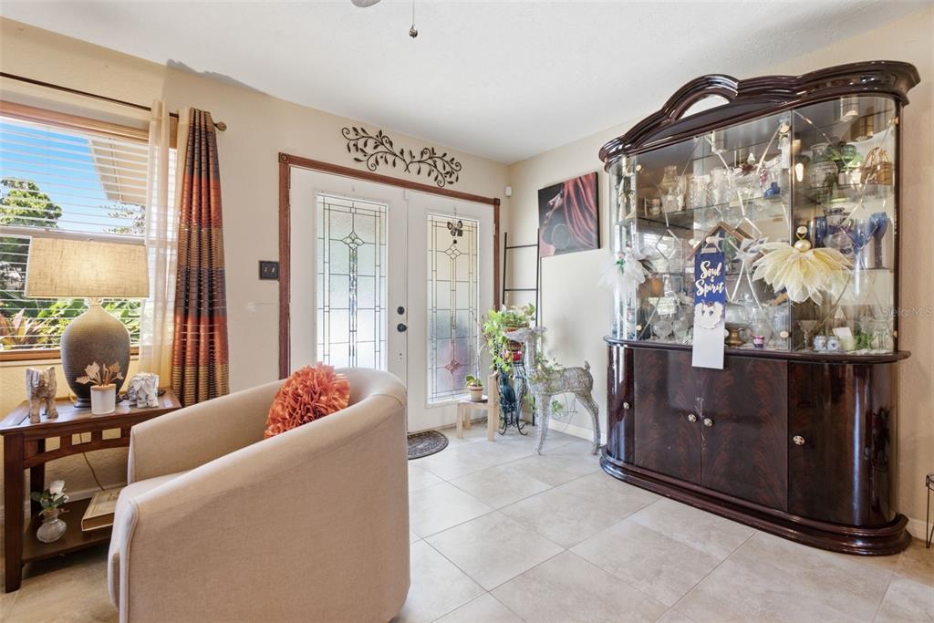 A brightly lit entryway features tile flooring, a large china cabinet, and a beige armchair — 701 58TH AVENUE S, ST PETERSBURG, FL