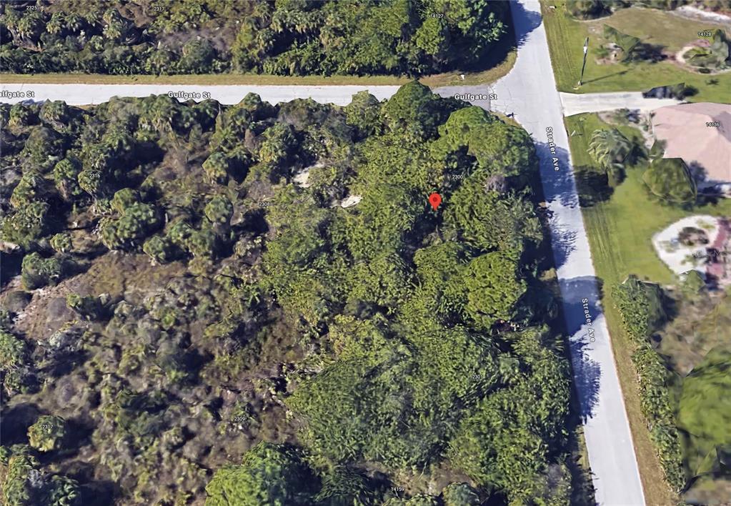 An aerial view shows a heavily wooded, undeveloped corner lot at the intersection of two streets — 14143 STRADER AVENUE, PORT CHARLOTTE, FL