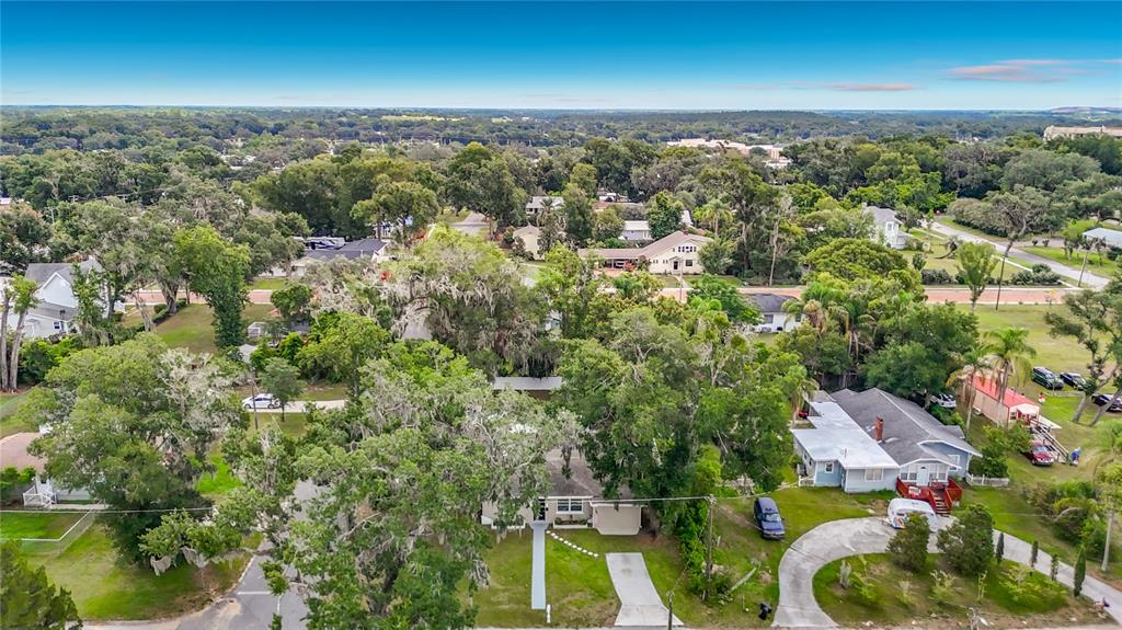 An aerial view shows a single-story house surrounded by mature trees and a residential neighborhood — 14402 13TH STREET, DADE CITY, FL
