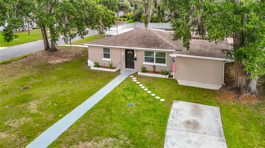 An aerial view shows a single-story house with a tan exterior, dark roof, and walkway — 14402 13TH STREET, DADE CITY, FL