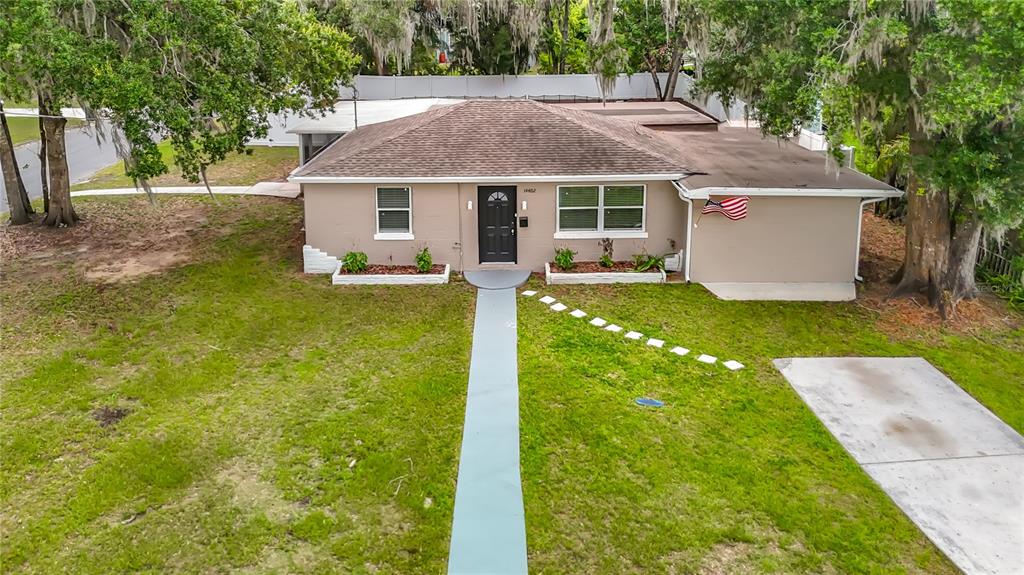 An aerial view of a single-story house with a tan exterior, dark roof, and walkway — 14402 13TH STREET, DADE CITY, FL