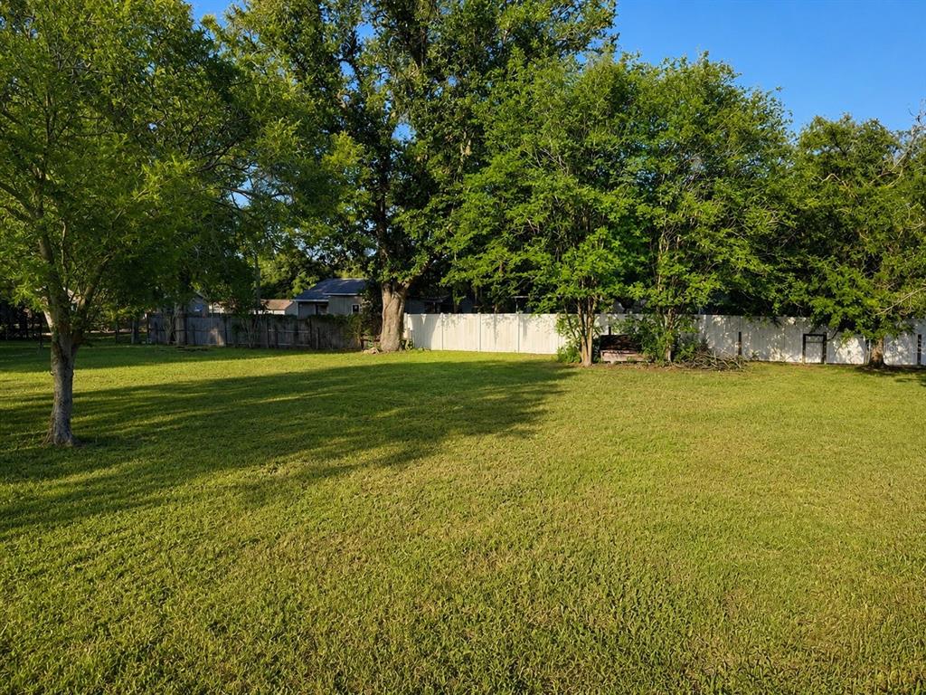 A large, grassy backyard features mature trees and a white vinyl privacy fence — SW 3RD CT, OCALA, FL