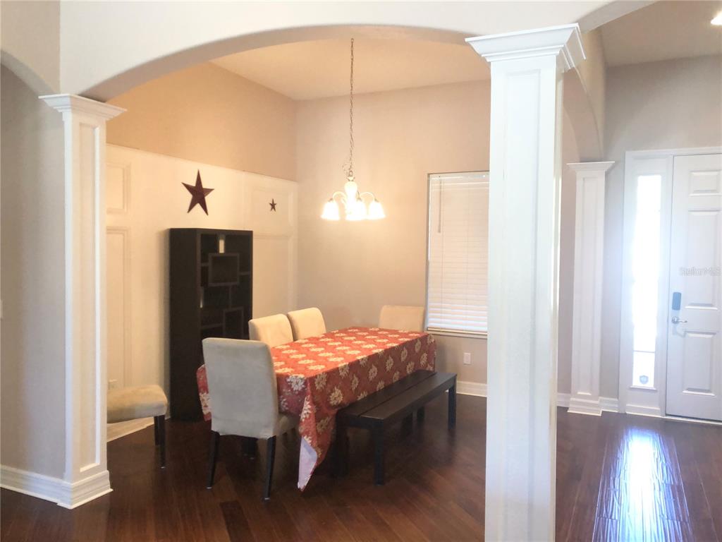 A dining room features dark wood floors, white columns, and a table with a patterned cloth — 19125 SWEET CLOVER LANE, TAMPA, FL