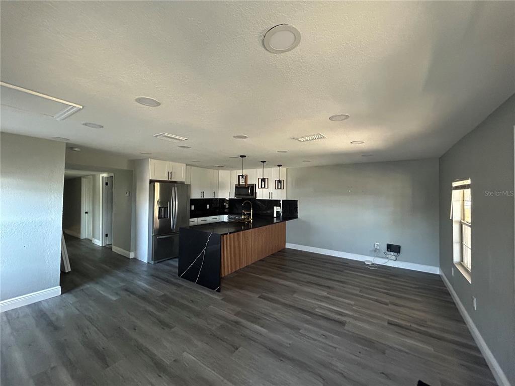 A kitchen with a black island, white cabinets, and gray wood-look flooring — 2119 E ELLICOTT STREET, TAMPA, FL