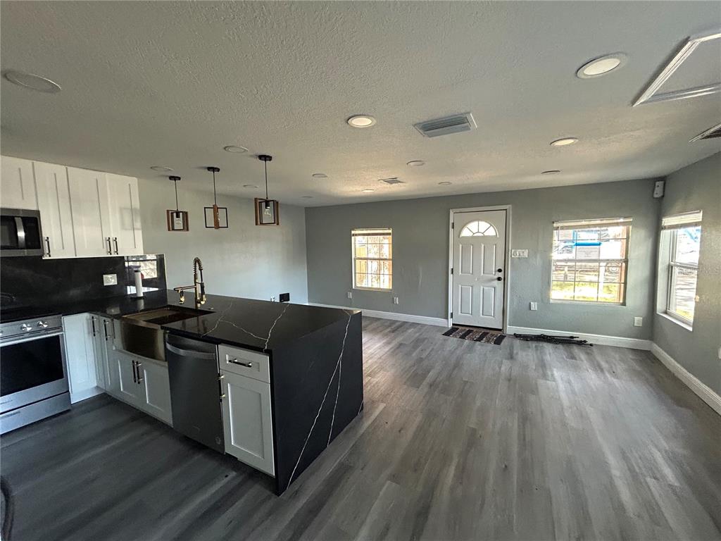 A kitchen with a black waterfall island and white cabinets opens into a living area — 2119 E ELLICOTT STREET, TAMPA, FL