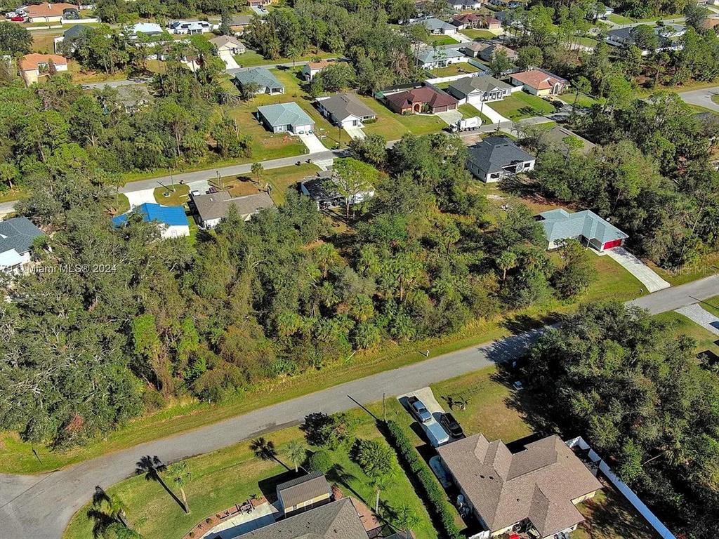 An aerial view shows a wooded vacant lot situated between several suburban residential homes — SARGON AVENUE, NORTH PORT, FL