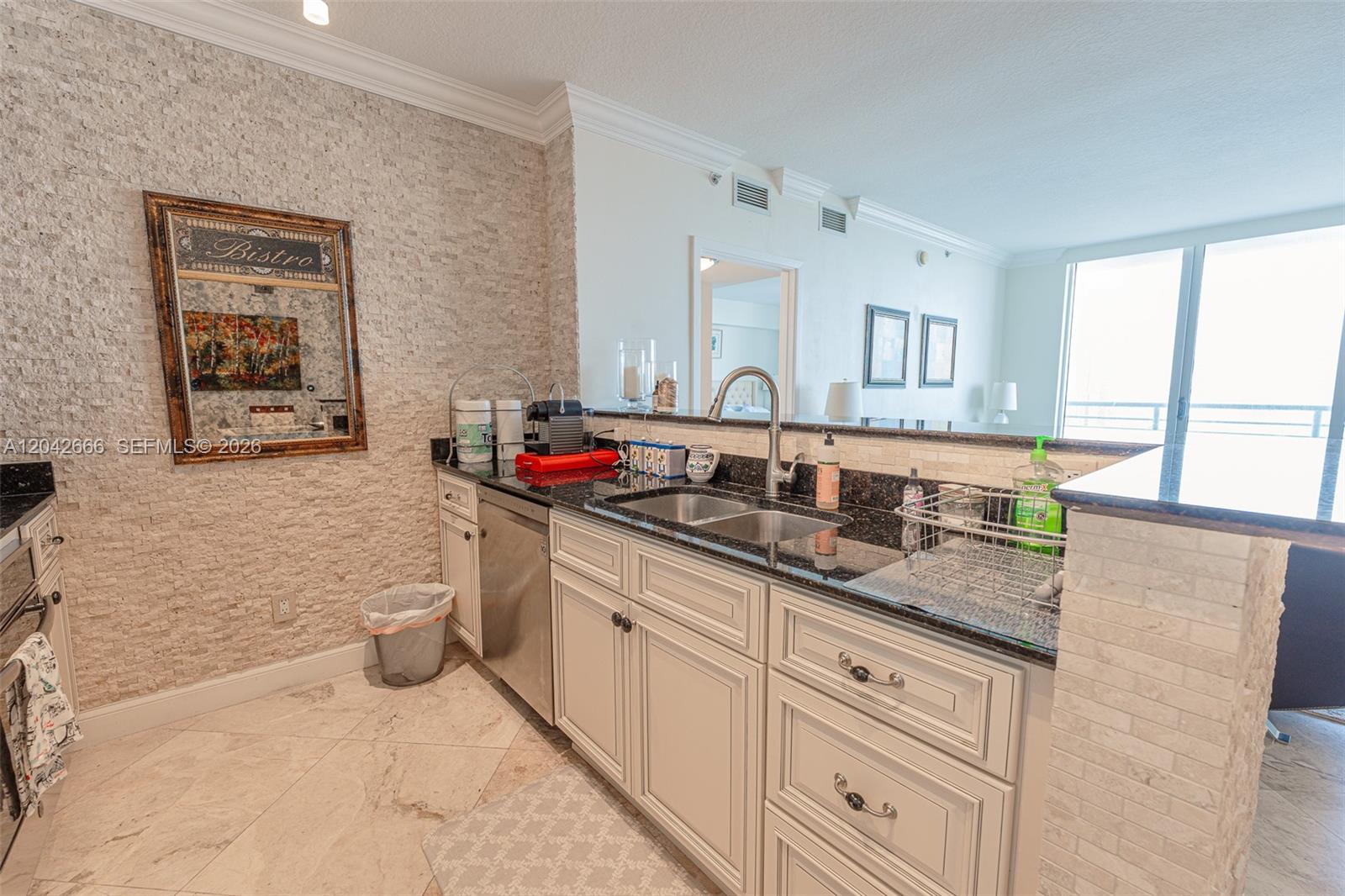 This kitchen features white cabinetry, dark granite countertops, and a textured stone accent wall — 325 S BISCAYNE BLVD # 4222, Miami FL 33131, MIAMI, FL