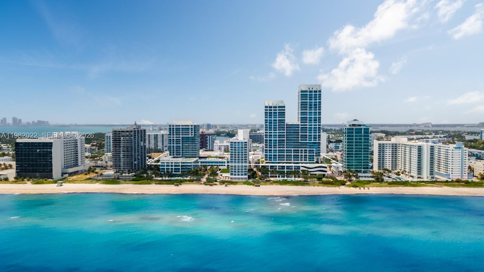 An aerial view shows several high-rise residential buildings situated directly along a sandy beach — 6799 Collins Ave # 209, Miami Beach FL 33141, MIAMI BEACH, FL
