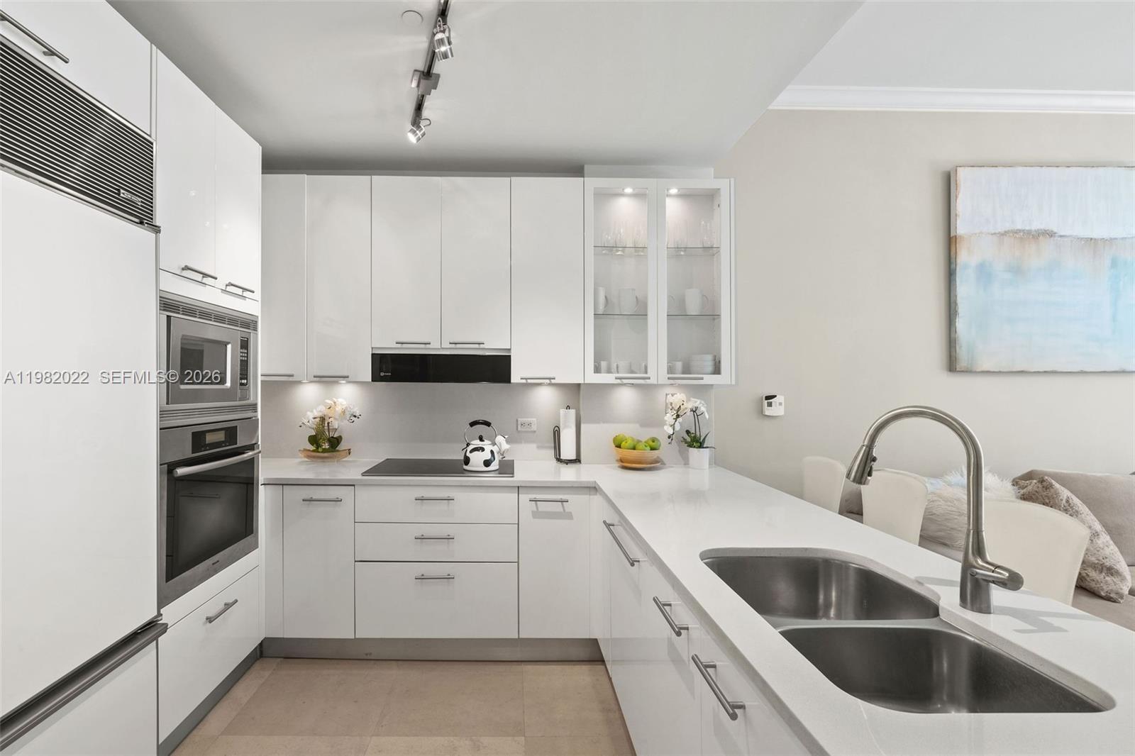 A modern kitchen features white cabinetry, stainless steel appliances, and a white quartz countertop — 6799 Collins Ave # 209, Miami Beach FL 33141, MIAMI BEACH, FL