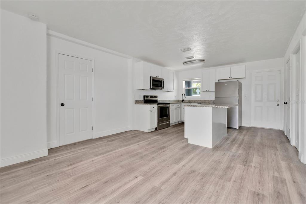 A kitchen with white cabinets, stainless steel appliances, a small island, and light wood flooring — 1409 COLLEGE PARK LANE, TAMPA, FL
